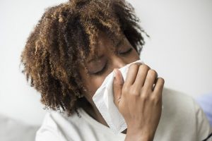 woman-sneezing-into-facial-tissue
